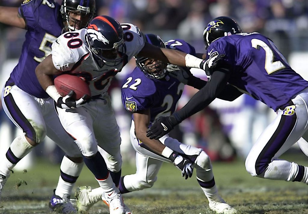 Tres jugadores de los Ravens del año 2000 rodeando a un rival que corre con el balón