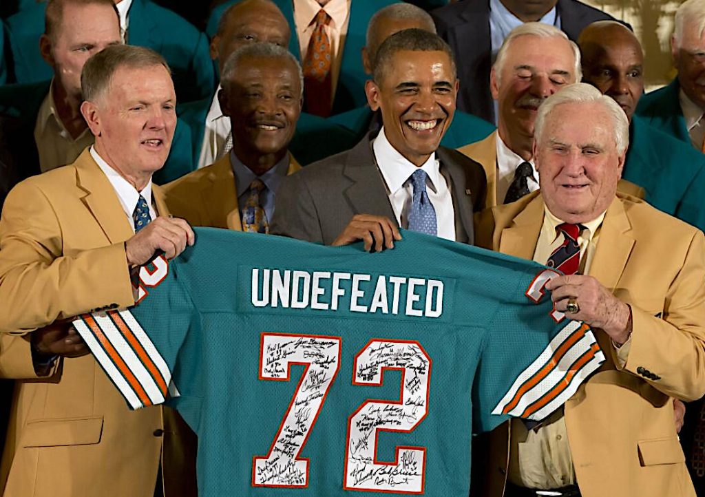 Barack Obama alzando una camiseta de los Dolphins del año 72